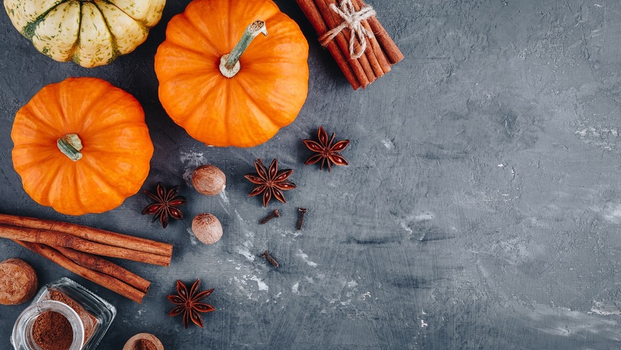 Various pumpkins, along with cinnamons, cloves and star anise, sit atop a slate board