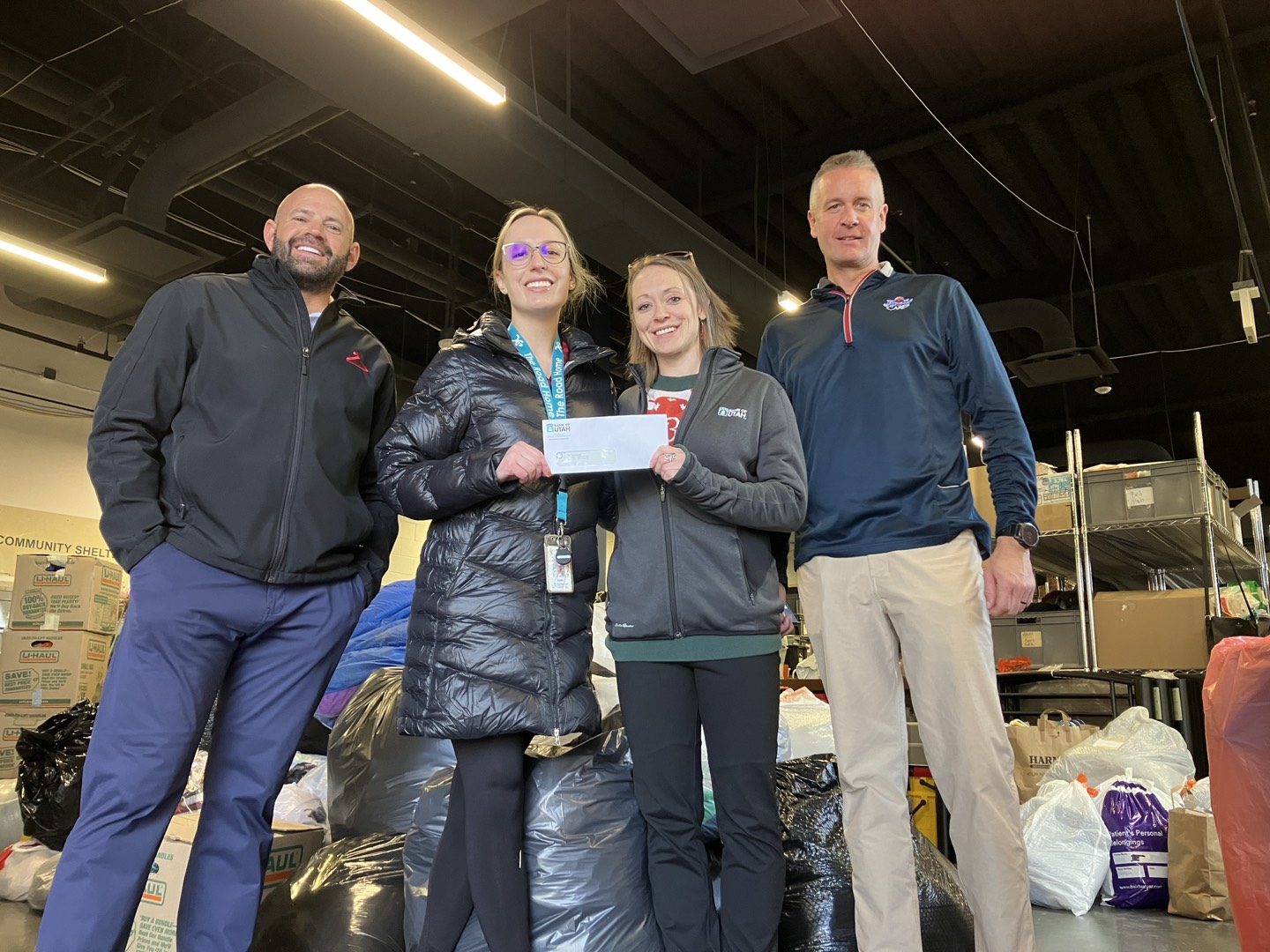 Ryan Fish of Red Hanger, Megan Kenley of Bank of Utah, and Joe Evans of Arctic Circle present a donation to Rachel Felton of The Road Home