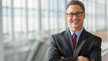 Business man in suit wearing glasses smiling.