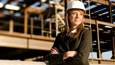 Business woman at construction site wearing hard hat.