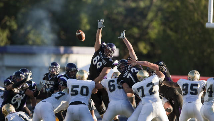 Action shot of Weber State football team attempting to block field goal.