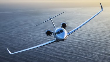 Aircraft owner trust.  Private jet flying over a body of water.